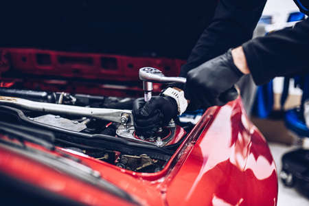 Mechanic in car service repairing engine or other car part