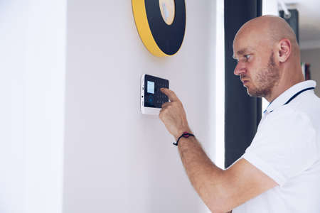 Man arming a home alarm on the wall.