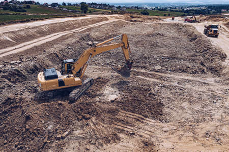 Aerial photo of excavator pours sand into the truck. On the construction site top view.の写真素材