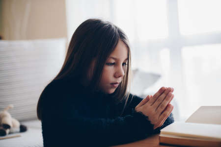 Girl praying with hands on bible. Concept for faith and religion.の写真素材