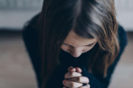 The girl is praying, hands folded in a prayer concept for faith and hope.の写真素材