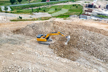 Yellow industrial excavator working on construction site. Aerial view.