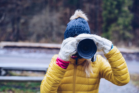 Young woman taking photos with a camera on a winter day.の写真素材
