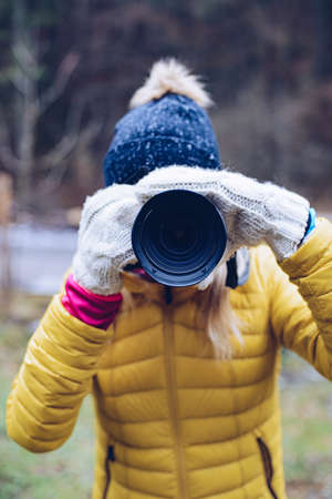 Young woman taking pictures on camera in winter day.の写真素材