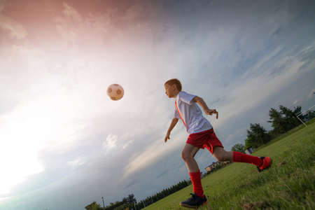 8 years old boy child playing football on playing field.の写真素材
