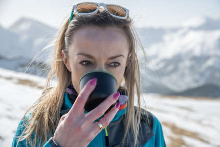 Close up portrait of mountain tourist woman drinking coffee or tea.の写真素材