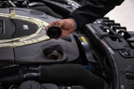 Service mechanic holding oil cap near engine.の写真素材