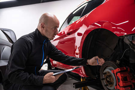 Mechanic or car service owner checking car and filling documentsの写真素材