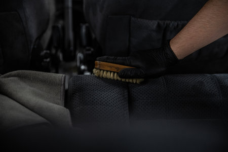 Man car detailing studio worker cleaning textile car upholstery