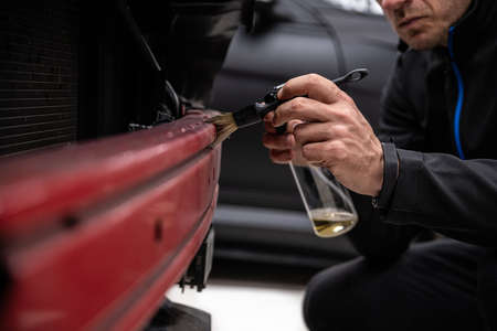 Car detailing studio worker carefully cleaning car with brushの写真素材