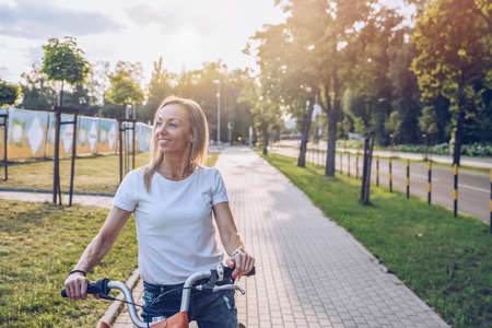 Beautiful and smiling adult woman enjoying a bike ride in sunny urban outdoors in the city.