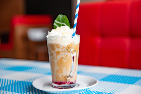 Iced caramel latte coffee in a tall glass with whipped cream.