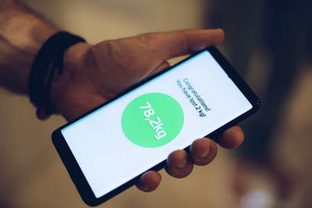 Man using weight loss application on his phone.の写真素材