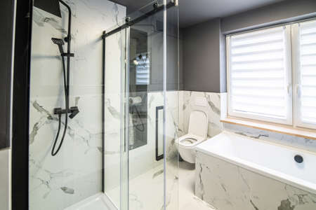 Modern flat bathroom with grey walls and bath and shower cabinの写真素材
