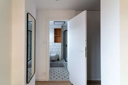 View from the hall to the entrance to the bathroom with a shower cabin and a toilet