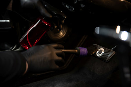 Employee of a car wash or a car detailing studio cleans the accelerator and brake pedalの写真素材