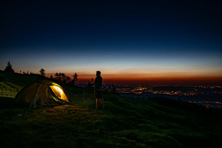 Male tourist stands next to a tourist tent on the summitの写真素材