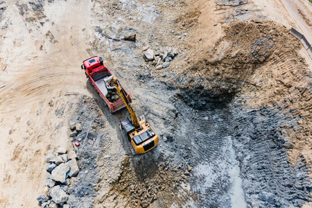 Excavator loading a truck with stones and road underlaymentの写真素材
