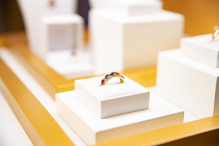 Gold ring with colorful gemstones presented on a white cushionの写真素材
