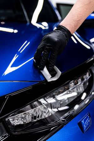 Car detailing studio or car wash worker applying ceramic car coating on blue carの写真素材
