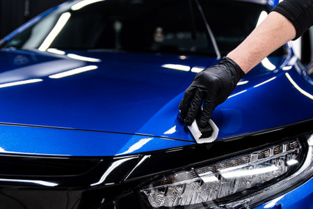 Car detailing studio or car wash worker applying ceramic car coating on blue carの写真素材
