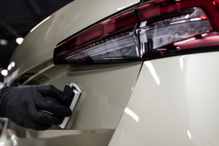 Ceramic coating application on rear car body panel near taillight during professional car detailingの写真素材