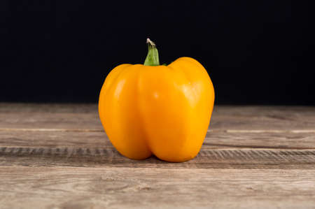 One yellow pepper on a wooden table
