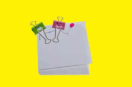 note paper and clip isolated on yellow backgroundの写真素材