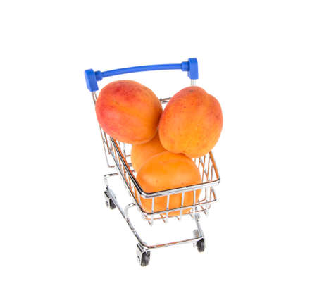 trolley from supermarket with apricot on isolated white backgroundの写真素材