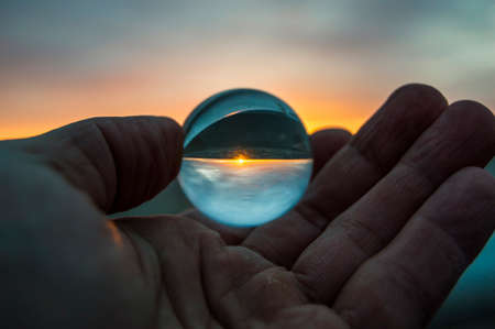 glass ball in hand on sunsetの写真素材
