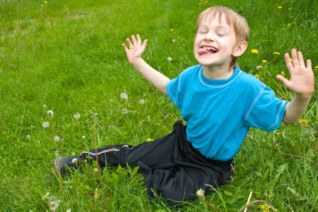 happy little boy laying on the grass in the parkの写真素材