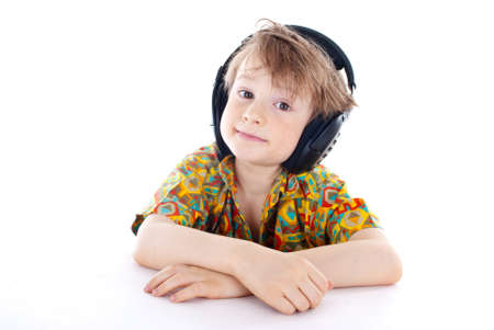 Portrait of a sweet young boy listening to music on headphones against white backgroundの写真素材