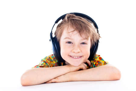 Portrait of a sweet young boy listening to music on headphones against white backgroundの写真素材