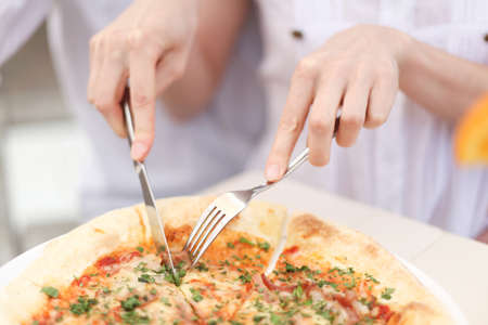 Cutting a  pizza with knife in cafe