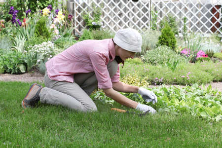 Young woman with hoe working in the garden bed