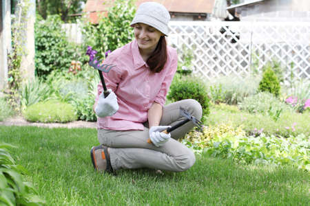 Young woman with rakes working in the garden bed