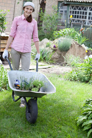 Portrait of woman with wheelbarrow in the gardenの写真素材