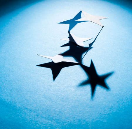 Paper christmas stars on the blue background .