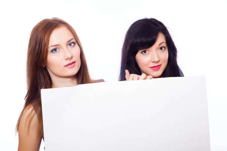 Two smily girls with a banner on the white background.の写真素材
