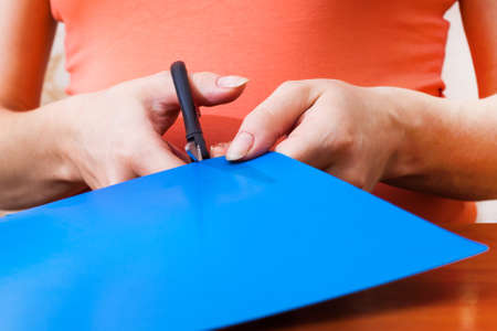Woman's hand cutting blue paper with scissors