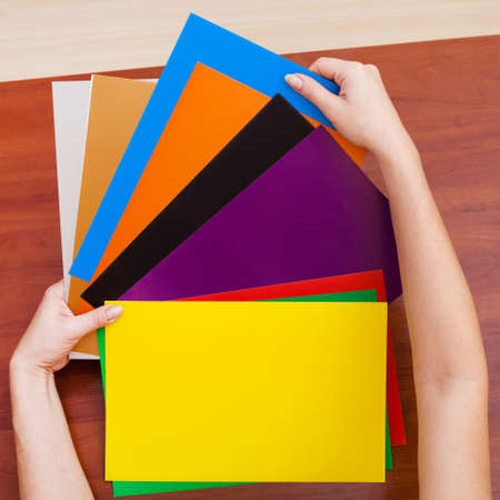 Woman's hands holding colorful sheets of paper