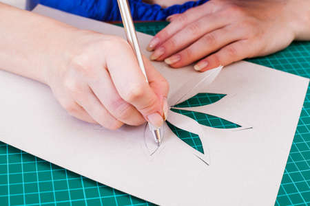 Woman's hand cutting out flower from paperの写真素材