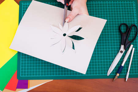 Woman's hand cutting out flower from paperの写真素材