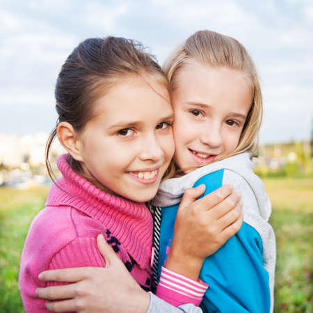 Two happy young women girl friends laughing in spring or summer outdoors backgroundの写真素材
