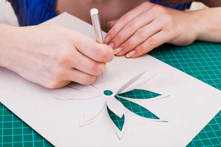 Woman's hand cutting out flower from paperの写真素材
