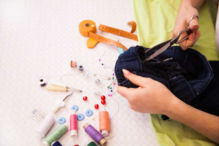A tailor doing alterations cutting a garment  in a workroom