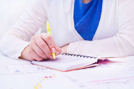 Business Woman Writing with pen in notepad at the office