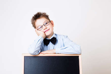 Portrait of a little boy holding a blackboard over gray backgroundの写真素材