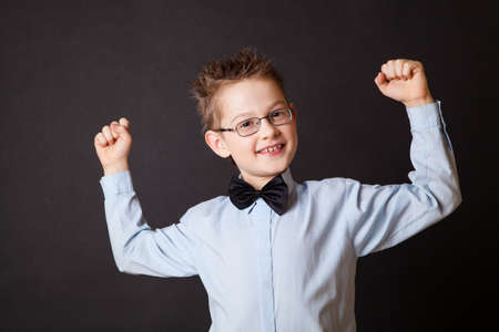 Little hapy boy showing his strength against the blackの写真素材