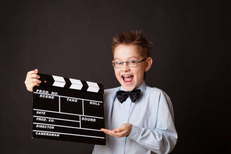 Little boy holding clapper board in hands. Cinema concept.
